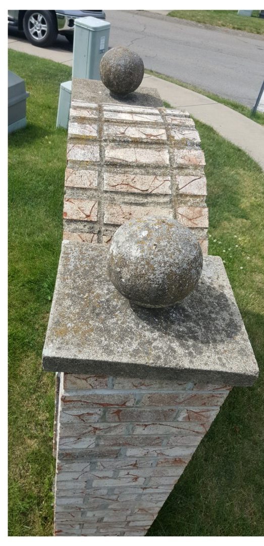 Stone entrance pillar before cleaning, covered in moss and lichen