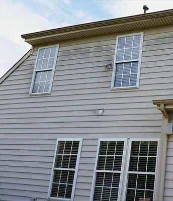 House siding before cleaning, streaked with dirt and mildew